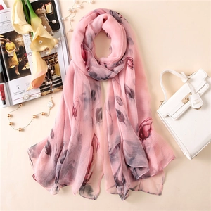 Detail of light pink floral silk scarf with elegant pattern and soft fabric texture