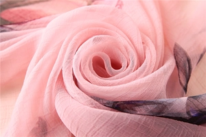 Macro shot of light pink pleated scarf fabric featuring deep purple floral prints