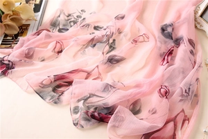 Macro view of light pink floral silk scarf featuring vintage red flower and leaf patterns