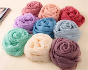 Detailansicht von neun eleganten Sonnenschutzschals, in Form von Rosenblüten gerollt