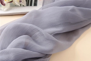 Makro-Detail des blaugrauen Chiffon-Schals mit feiner Faltenstruktur und Textur