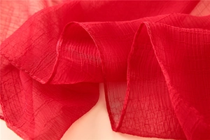 Nahaufnahme eines eleganten roten Sonnenschutzschals mit Plissee-Textur und feinen Nähten
