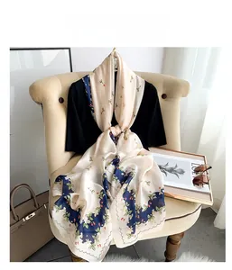 Detail of floral strawberry print silk scarf with elegant scalloped edges on armchair