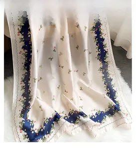 Detailed view of floral and strawberry silk scarf with navy blue wavy edge craftsmanship