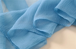 Makro-Detail von hellblauem plissiertem Chiffonstoff mit eleganter Textur und Saumkanten
