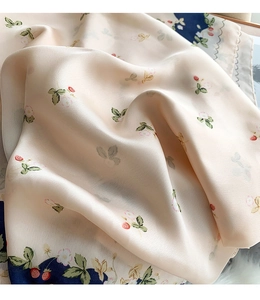 Detailed texture of silk floral scarf featuring red strawberry and green leaf patterns