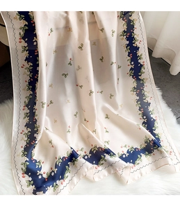 Detailed texture of silk-like scarf with floral and strawberry print on soft plush background