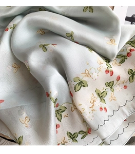 Detail of silk-feel scarf showing floral strawberry print and black scalloped edges