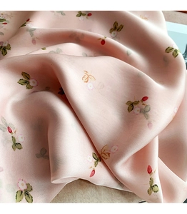 Detailed close-up of pink floral silk scarf fabric showing strawberry patterns and soft texture