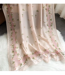 Detailed texture of a soft pink silk scarf with floral patterns and strawberry prints