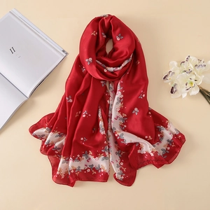 Close-up of red floral silk scarf with soft draped texture and delicate petal patterns