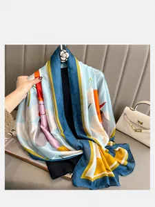 Detail of silk scarf with blue border and yellow floral print and camellia brooch