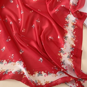Close-up of red floral silk scarf showing delicate strawberry print and wavy edge details