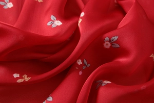 Macro detail of red floral silk scarf fabric with elegant patterns and satin finish