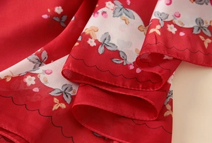 Detailed macro view of red strawberry print silk scarf with wavy stitched edges