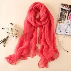 Nahaufnahme des korallenroten Chiffon-Schals mit feiner Plissee-Struktur und weichem Stoff