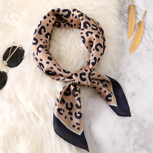 Fashionable leopard print silk scarf for women on white marble background with sunglasses
