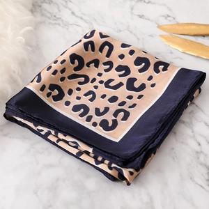 Detail of silk leopard print square scarf with navy blue borders on marble background