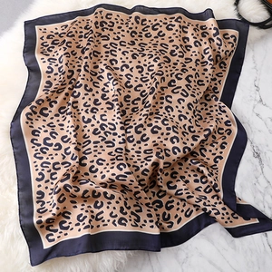 Detail of leopard print square silk scarf with dark border on white plush background