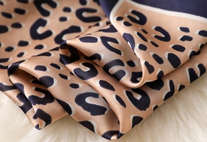 Close-up of leopard print silk scarf with satin finish and soft fabric texture folds