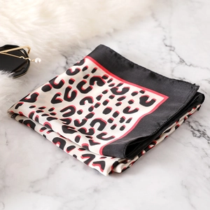 Detail of leopard print silk scarf with red accent lines and smooth satin texture
