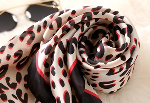 Macro shot of red and black leopard print silk scarf with smooth draped texture