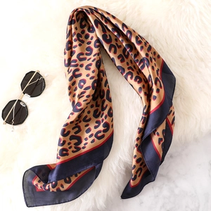 Detail of leopard print silk scarf in gold and navy on a soft plush background
