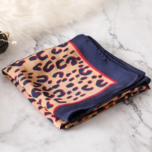 Detailed view of leopard print silk scarf with navy borders on white marble surface