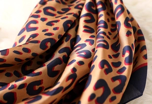 Macro shot of leopard print silk scarf texture on white faux fur background
