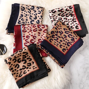 Flat lay view of leopard print silk square scarves in multiple colors on white faux fur