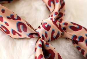Macro shot of silk leopard print scarf knot showing smooth texture and pattern