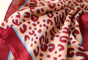 Detailed view of leopard print silk scarf showing soft burgundy folds and luxurious texture