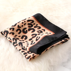 Detailed view of leopard print silk scarf with black border on soft faux fur background