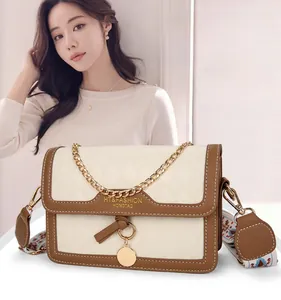 Detail of a cowhide leather flap bag with brown trim and gold chain strap in a lifestyle setting