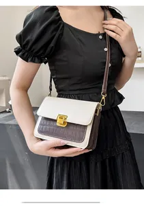 Close-up of retro crossbody bag with beige and brown crocodile texture and gold clasp