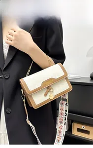 Detail of quilted crossbody bag with brown trim and ethnic embroidery strap