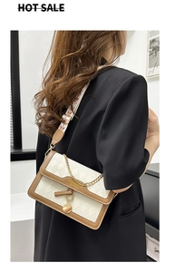 Detailed view of white quilted square bag with brown leather and wide patterned strap