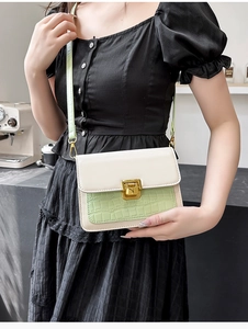 Detail of mint green crocodile pattern faux leather and golden rotary buckle on a square bag