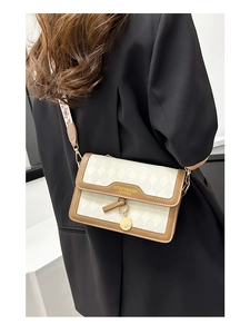 Detail of white quilted crossbody bag with patterned wide strap and gold hardware accents