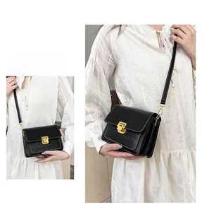 Detail of black crossbody bag featuring crocodile texture and golden square twist lock