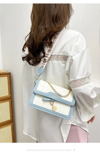 Detail of color block crossbody bag with embroidered wide strap and metallic gold chain