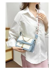 Detail of blue and white crossbody bag with gold chain and wide patterned strap