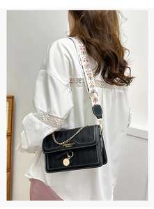 Detail of black quilted crossbody bag with ethnic print wide strap and gold chain