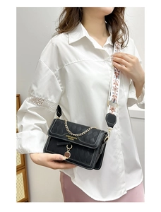 Detail of black quilted PU leather crossbody bag with ethnic patterned wide strap