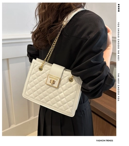 Detail of white quilted handbag with golden chain strap and branded metallic buckle