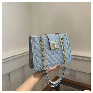 Detail of light blue quilted leather bag with gold metal chain and square lock closure