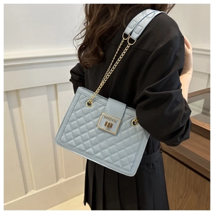 Detail of light blue quilted crossbody bag with gold chain strap on a model shoulder