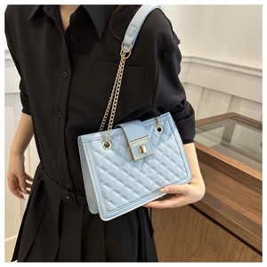Close-up of light blue quilted chain bag with gold metal twist lock and quilted texture