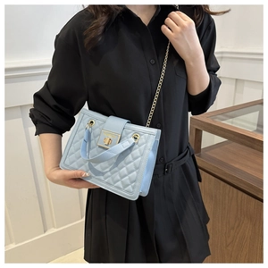 Detail of light blue quilted crossbody bag with gold chain strap and metallic lock