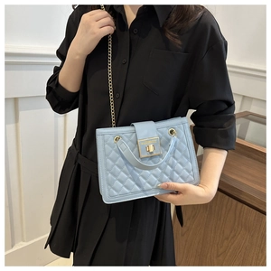 Detail of light blue quilted chain bag with gold square lock and elegant top handle